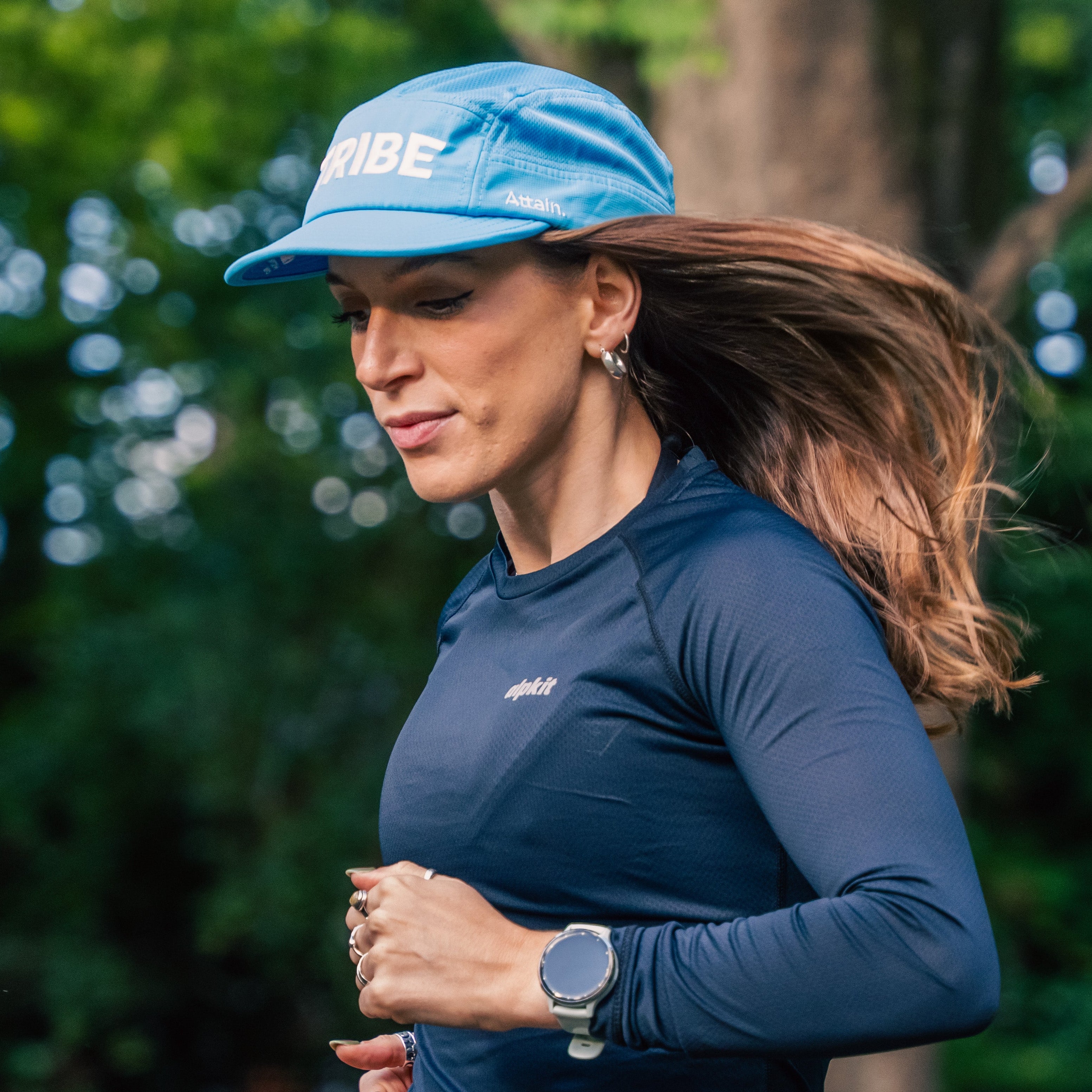 Woman running outdoors wearing a blue cap and shirt with visible branding.